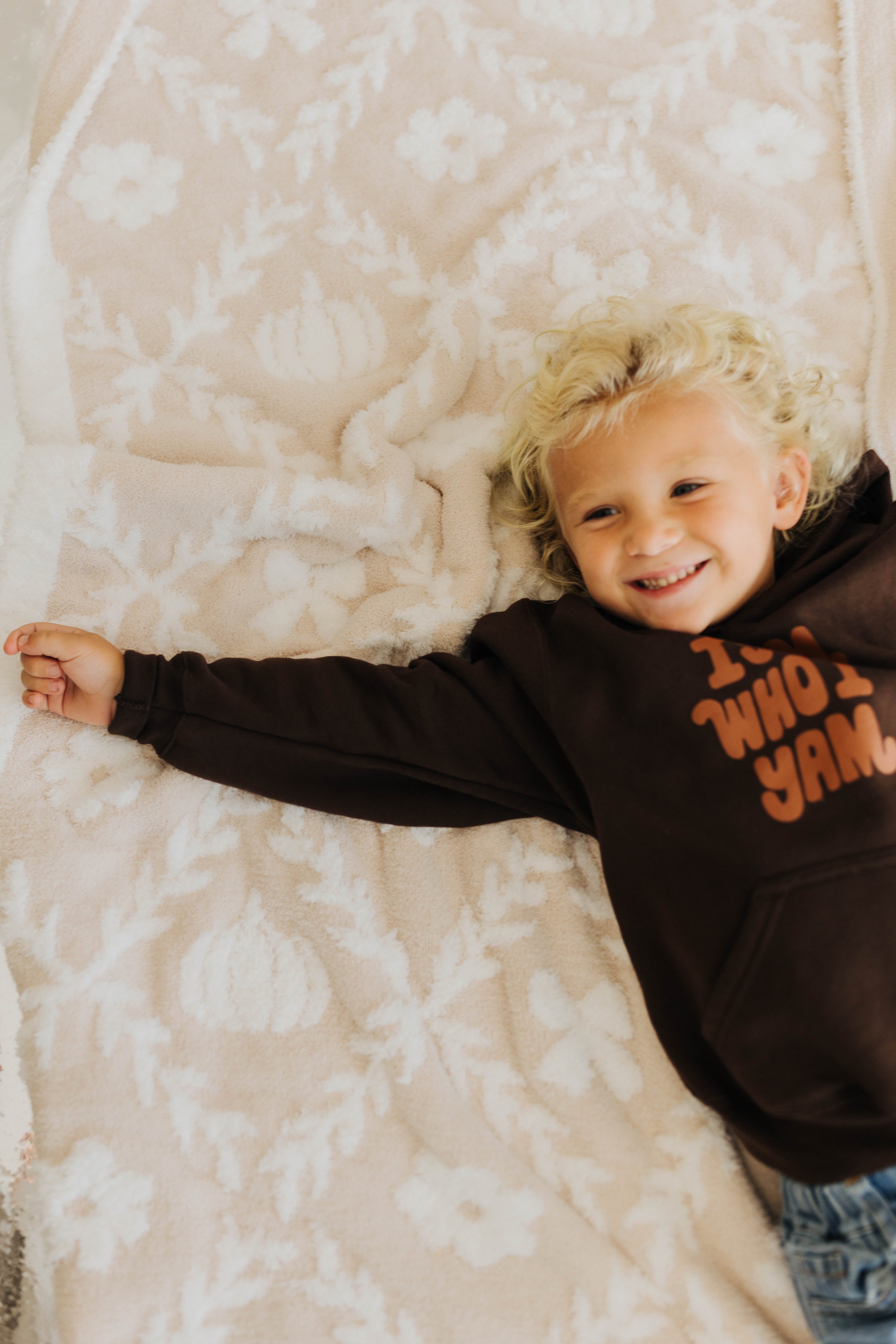 little boy laying on pumpkin blanket smiling 