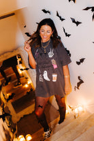 model krista in the staircase leaning up against the wall smiling wearing hot ghoul halloween tee with halloween graphics and candles and bat decorations in the background 