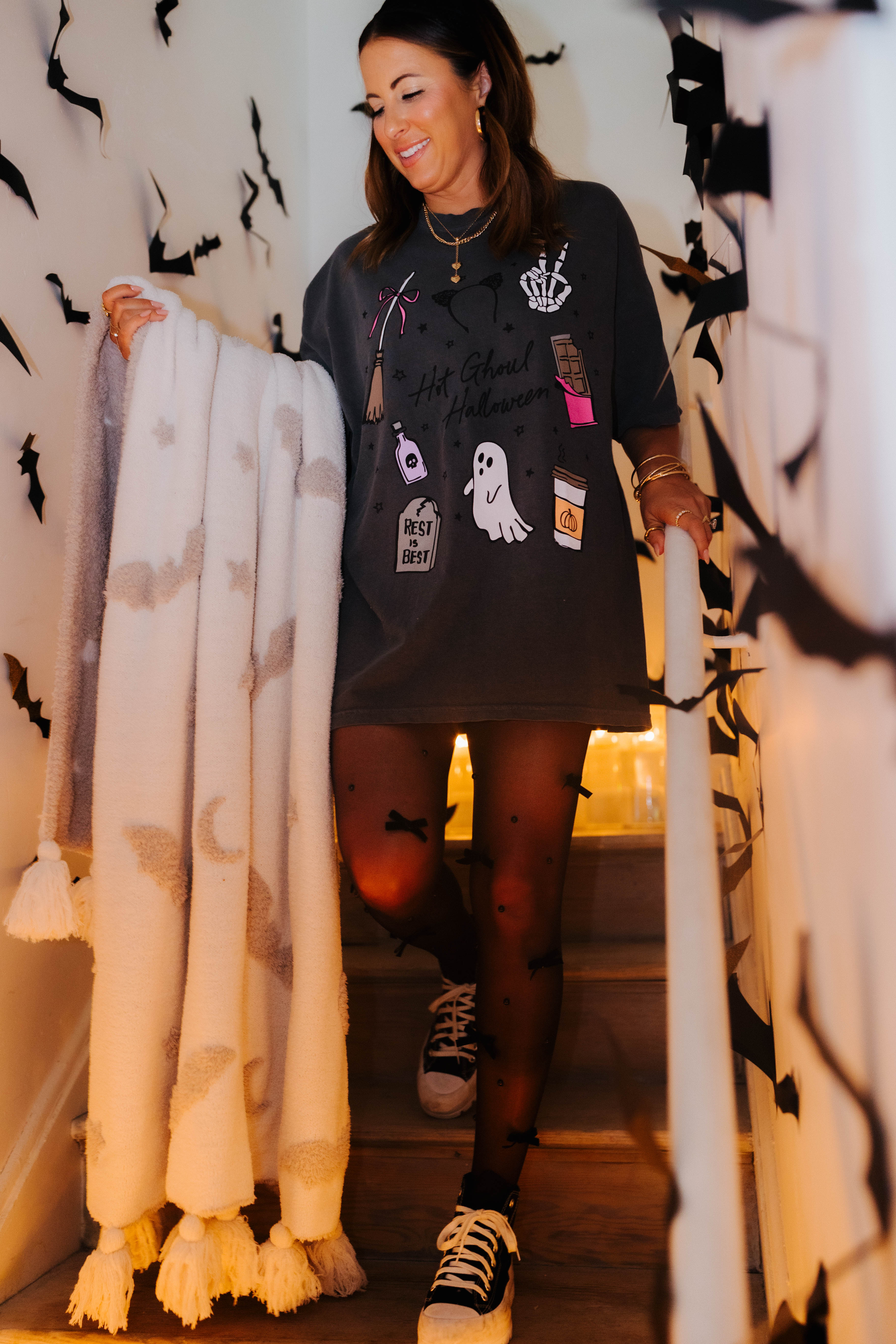 model krista on the staircase wearing hot ghoul tee holding the bat blanket with bat decorations in the background 
