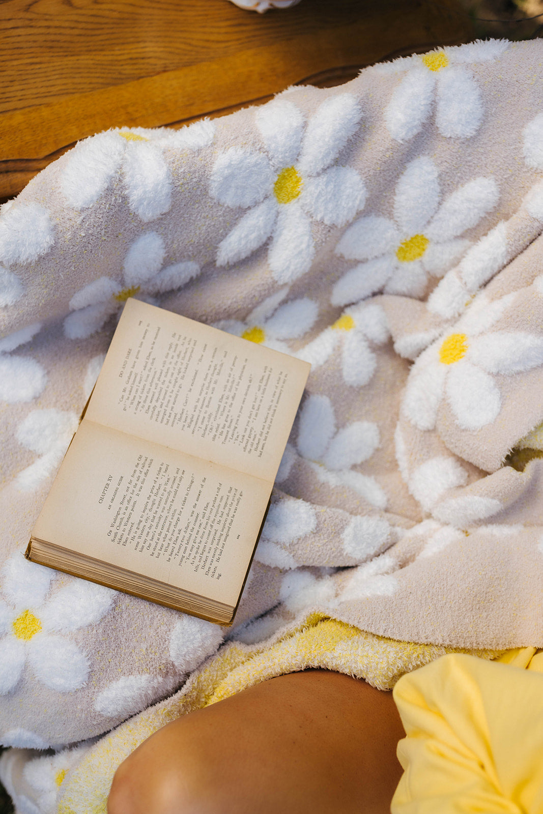 Open book on a floral-patterned blanket with a yellow edge.
