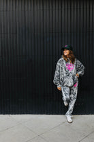 model wearing hot mess at heart camo set smiling leaning against black wall 