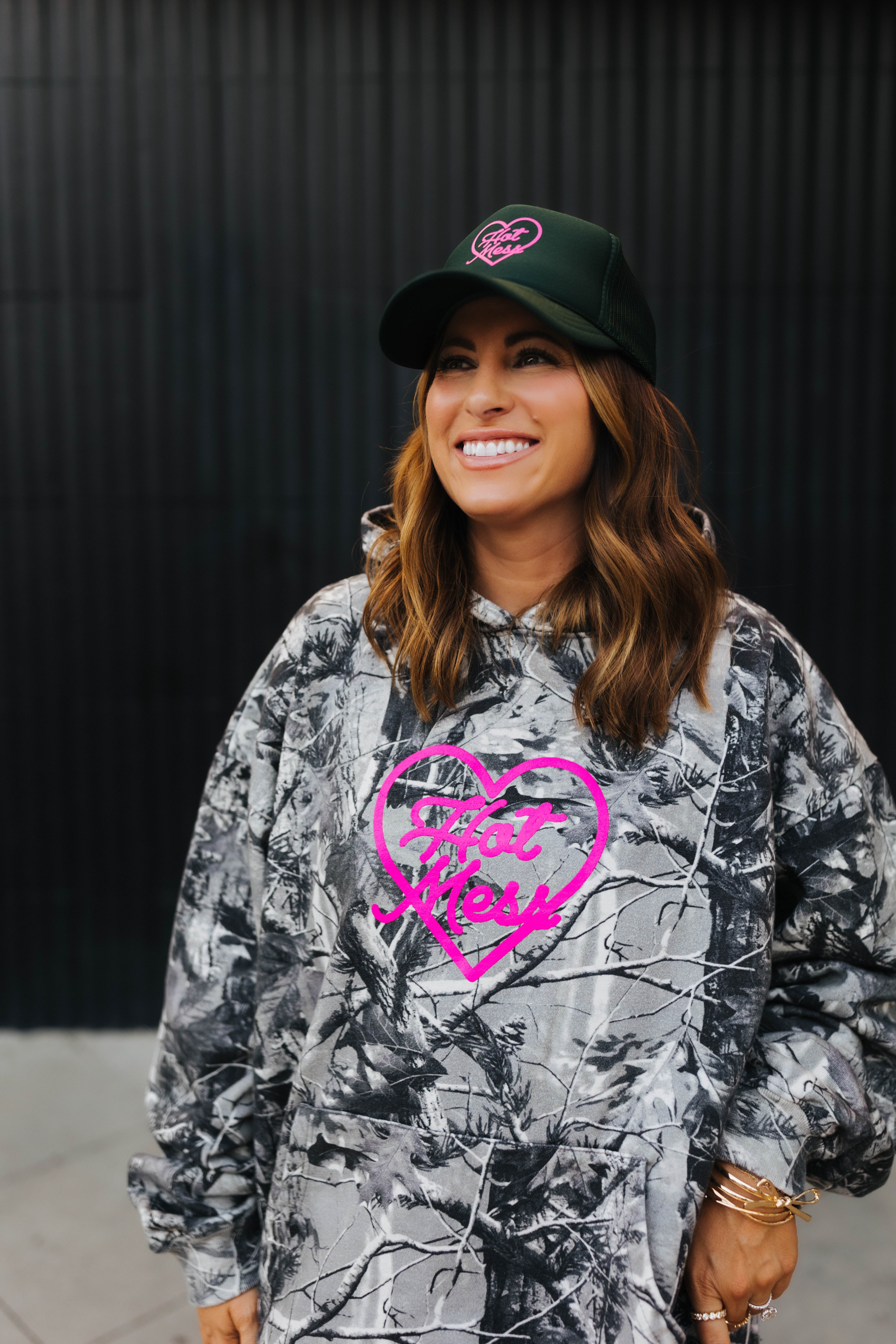 close up of model wearing hot mess at heart camo hoodie and hot mess at heart hat 