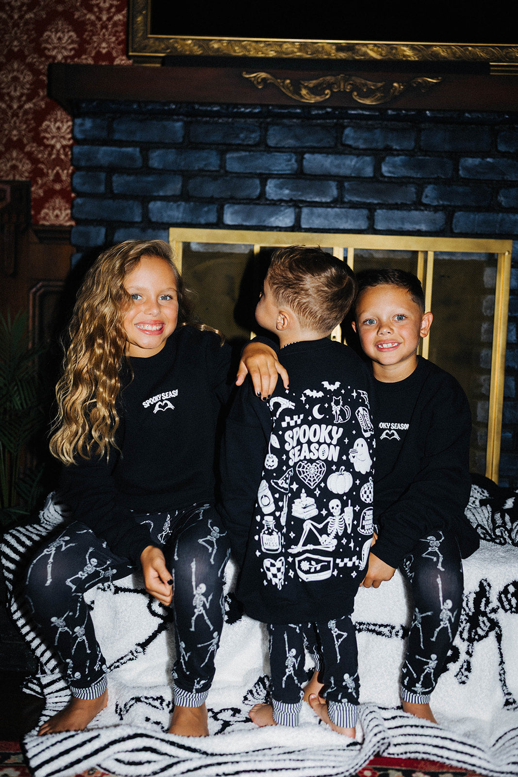 3 kids sitting on a fireplace in matching pjs and sweatshirts