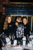 3 kids sitting on a fireplace in matching pjs and sweatshirts