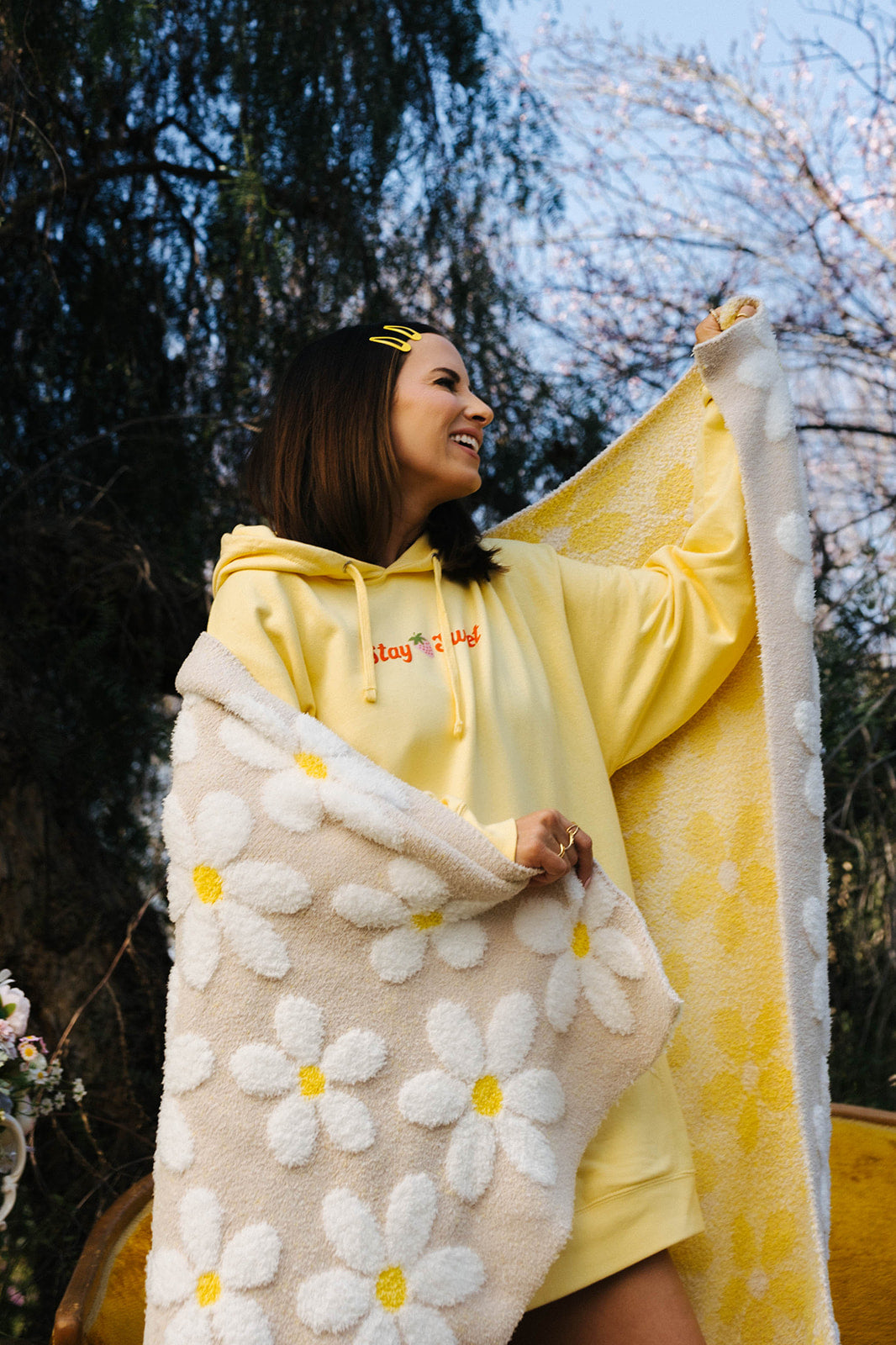 Person wrapped in a yellow blanket with floral patterns outdoors