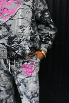 model close up wearing hot mess at heart camo set with hand in pocket against black wall 