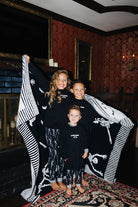 three kids holding blanket around them in matching pjs and sweatshirt