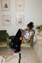 model sitting in chair wearing camo tee holding and looking at hot mess bomber jacket 