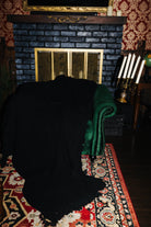 Black waffle fringe blanket draped over a green chair