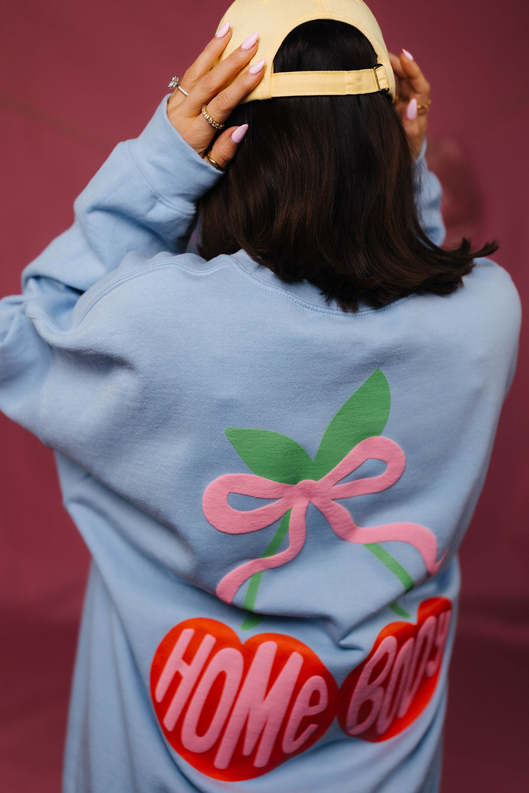 Person wearing a light blue sweatshirt with a colorful design and text on a red background