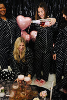 Group of women in polka dot pajamas celebrating with balloons and drinks.