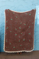 Back side of the cherry blanket showing the white scallop edge and mostly red background against a blue wall