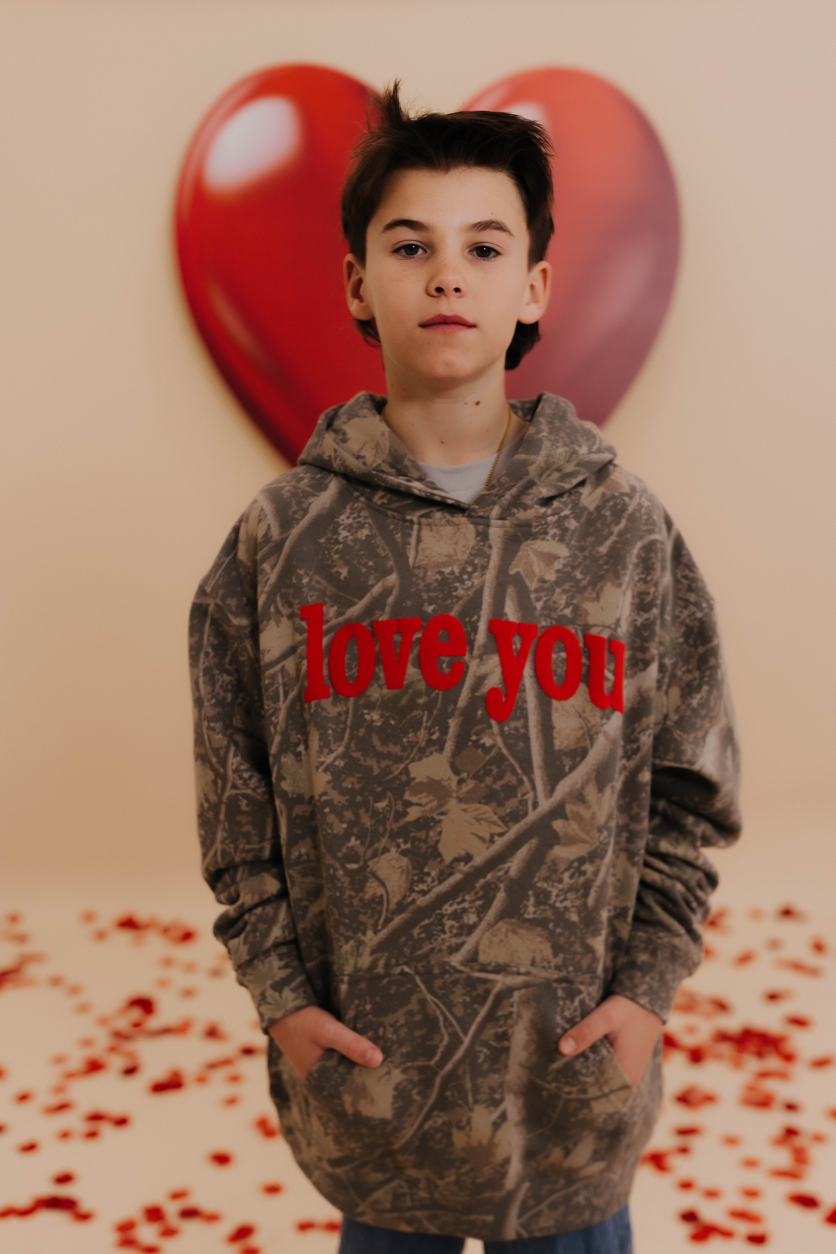 Boss in a camo kids XL sweatshirt that says love you