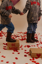 Kids holding hands while walking on books that say be mine