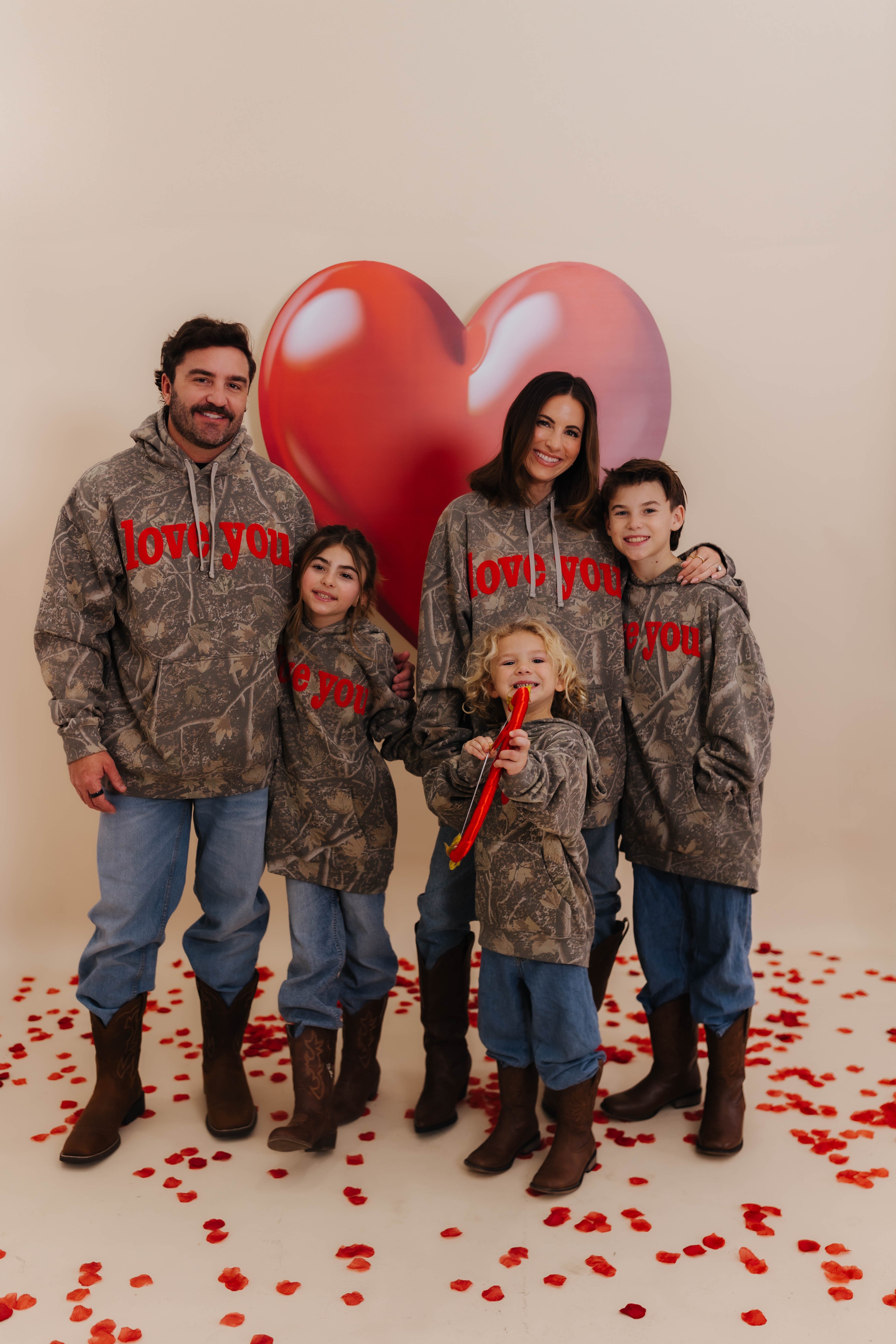 the full fam in matching camo sweatshirts that say love you with red puff print
