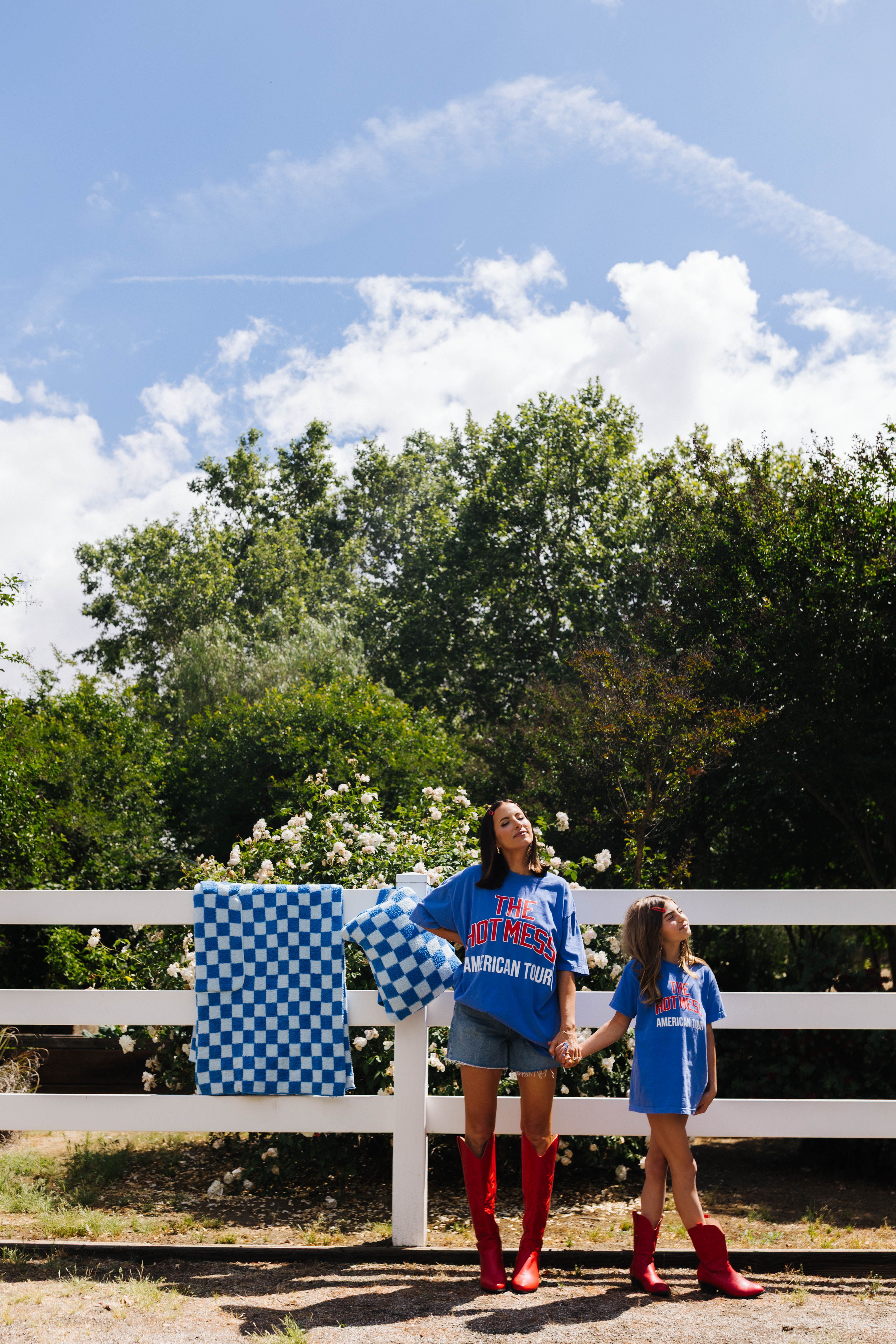 girl and daughter standing in front of white fence with quillow behind it 