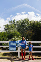 girl and daughter standing in front of white fence with quillow behind it 