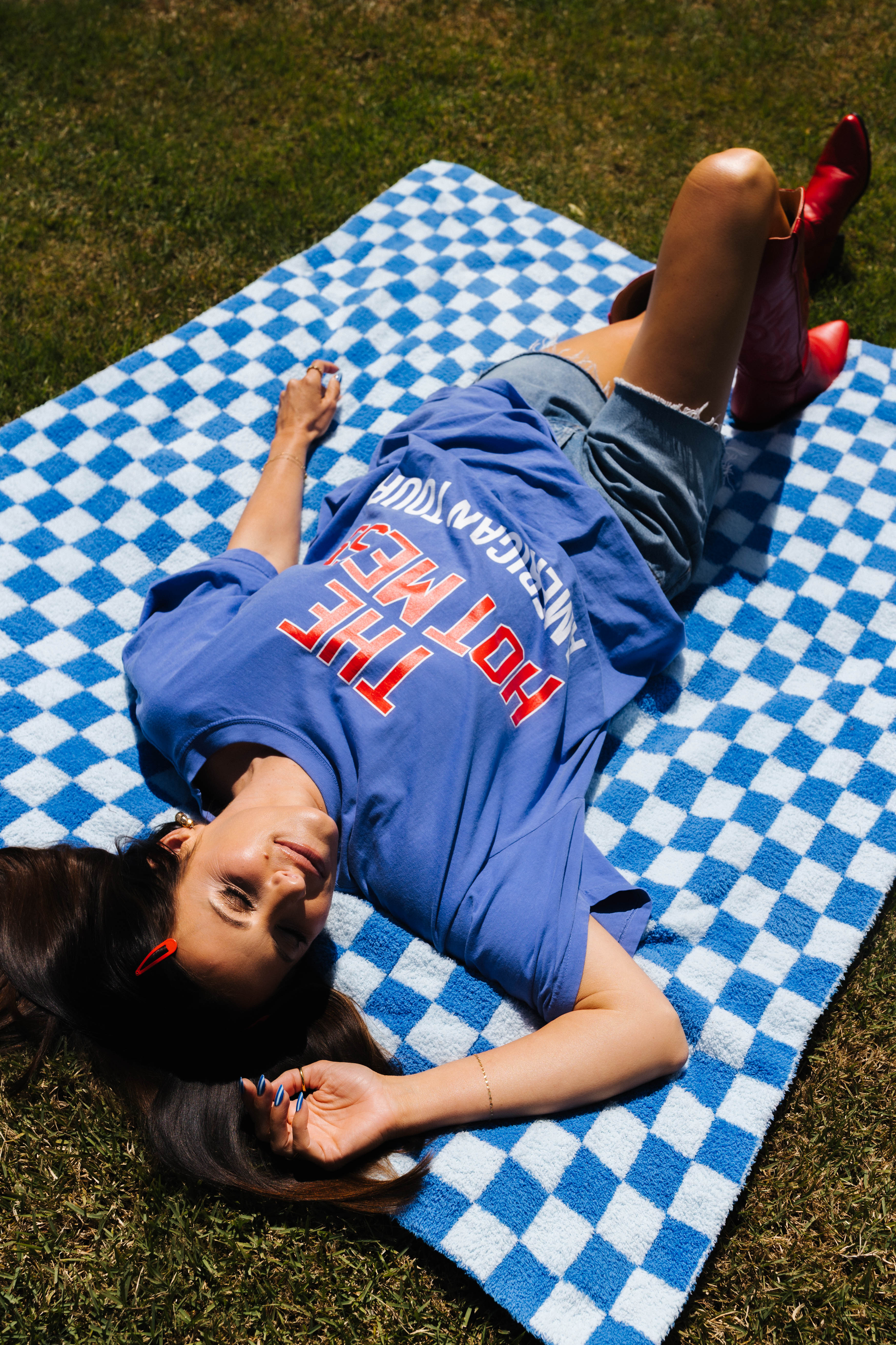 woman laying on blue check blanket in the grass