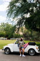 photo of Krista posing in front of the bug that has the american flag styled on it 