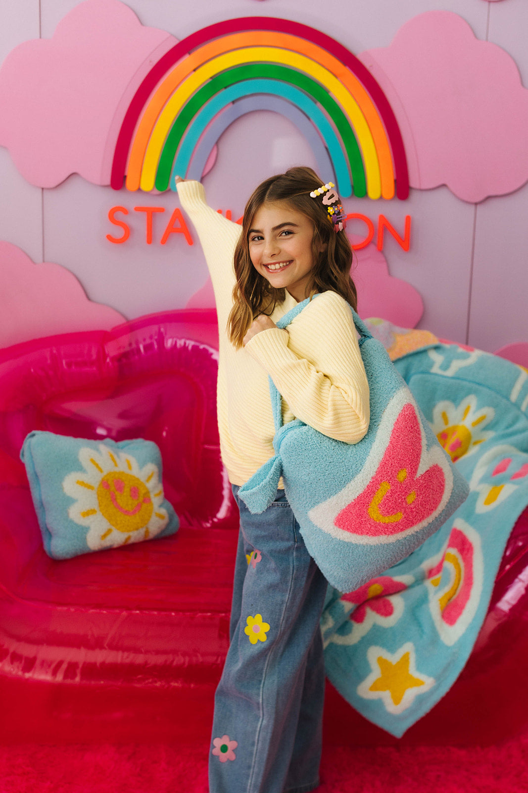 Young girl holding a colorful blanket with a rainbow and bright decor in the background