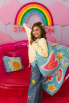 Young girl holding a colorful blanket with a rainbow and bright decor in the background