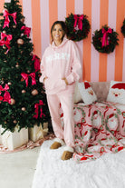 Person wearing a pink hoodie and pants in a festive room with Christmas decorations.