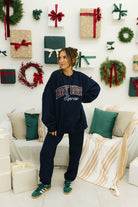 Woman wearing a navy sweatshirt with 'Hot Mess Express' text in a festive room with Christmas decorations.