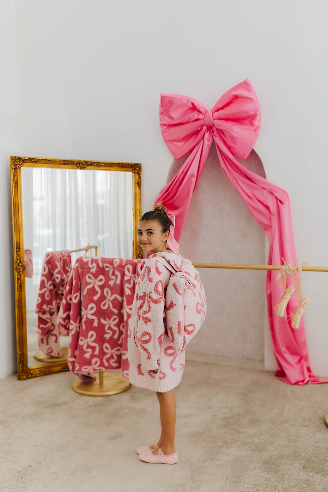 Person wearing a pink robe with a pink bow pattern in a room