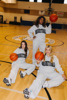All three woman wearing matching outfits on the basketball court holding basketballs 