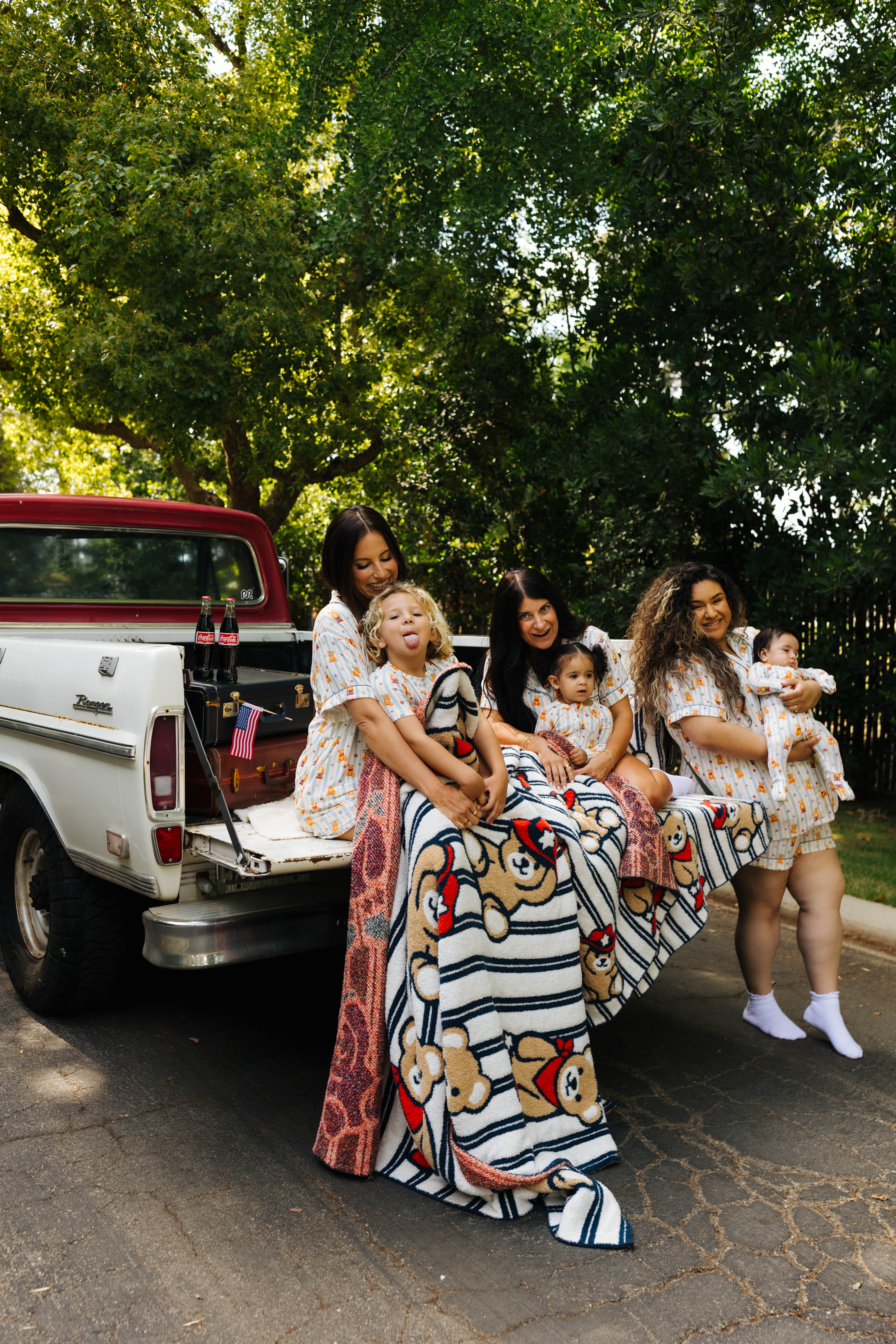 moms and kids sitting on the back of the truck with the teddy blanket over them