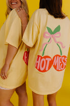 Two women wearing yellow t-shirts with 'HOT MESSES' text and graphics on a yellow background
