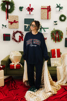 Person wearing a navy sweatshirt with text in a festive room with Christmas decorations.