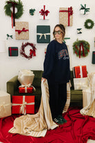 Person wearing a dark blue sweatshirt with text, standing in a festive room with Christmas decorations.