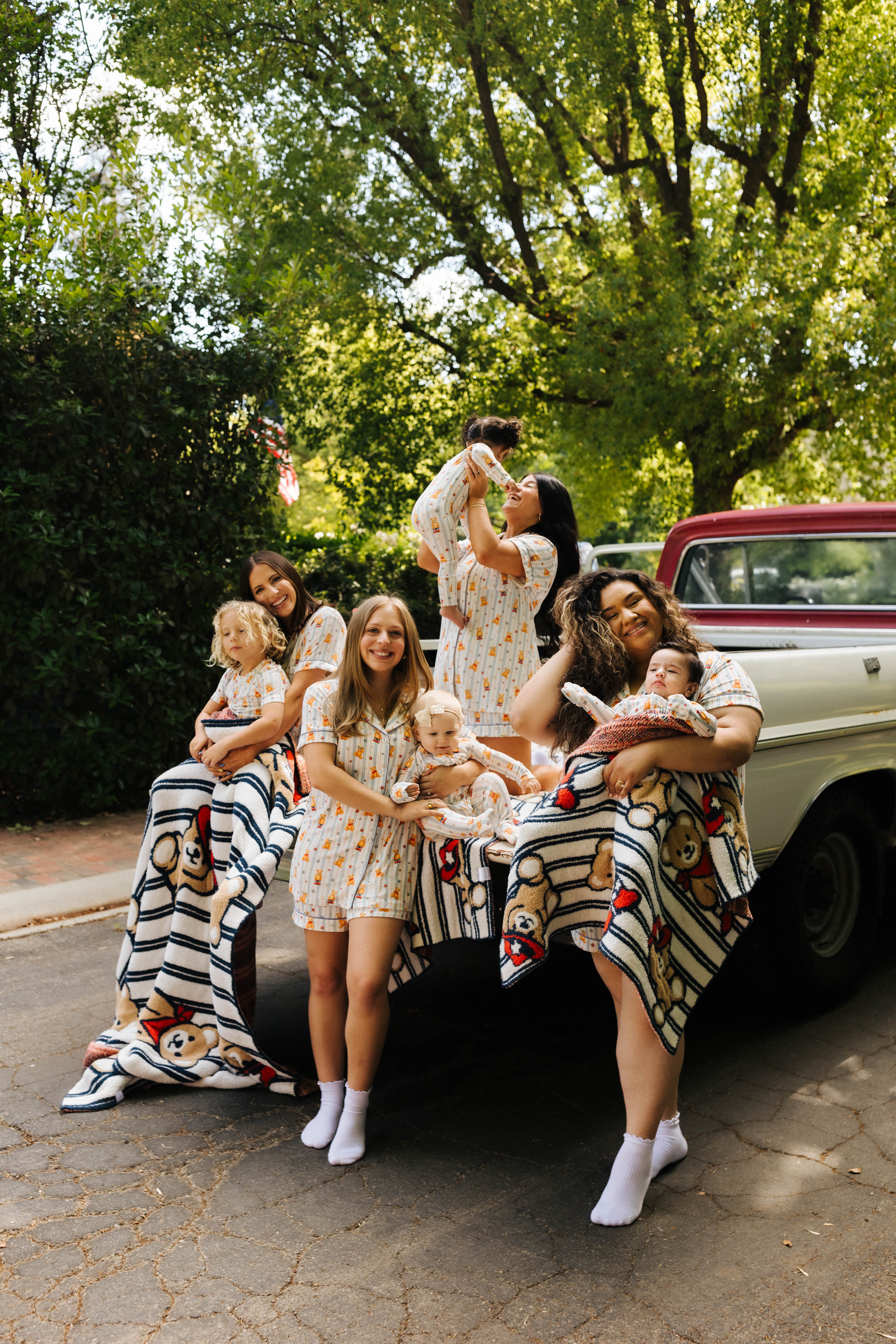 women and their kids in the back of a truck in teddy pjs wrapped in teddy blankets