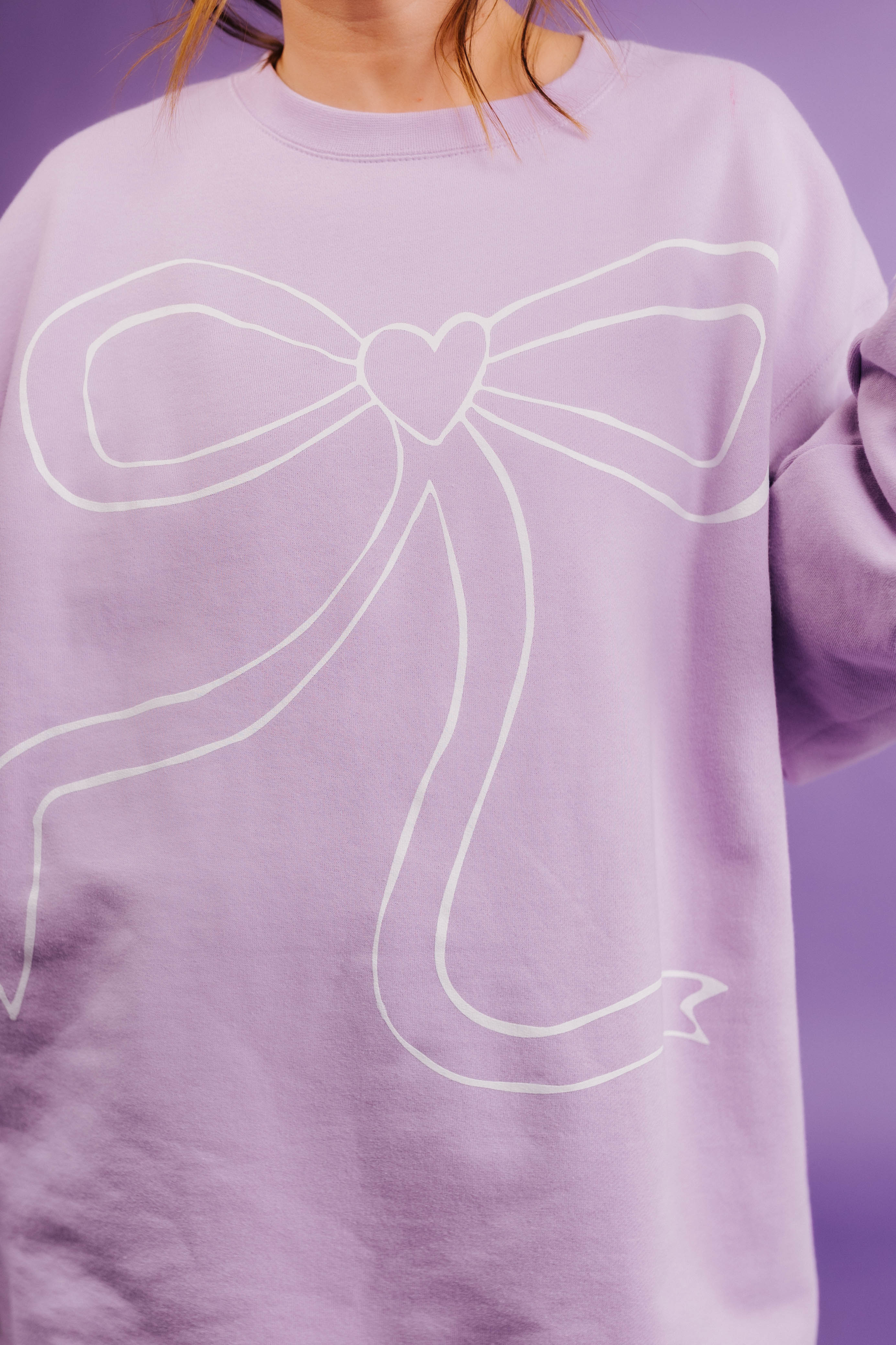Purple sweatshirt with a white bow design on a purple background