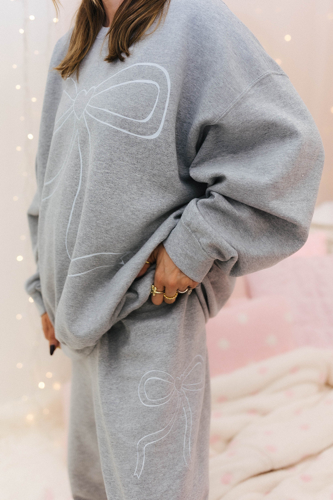 Person wearing a gray sweatshirt with white designs against a soft, blurred background