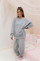 Woman wearing a grey loungewear set with a bow design in a cozy room.