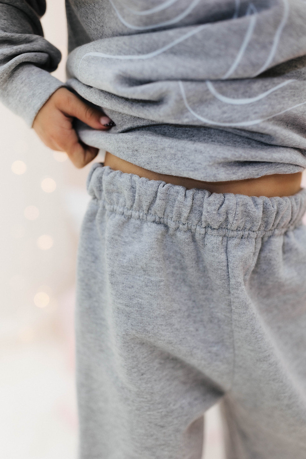 Person wearing a gray sweatshirt and sweatpants with a blurred background