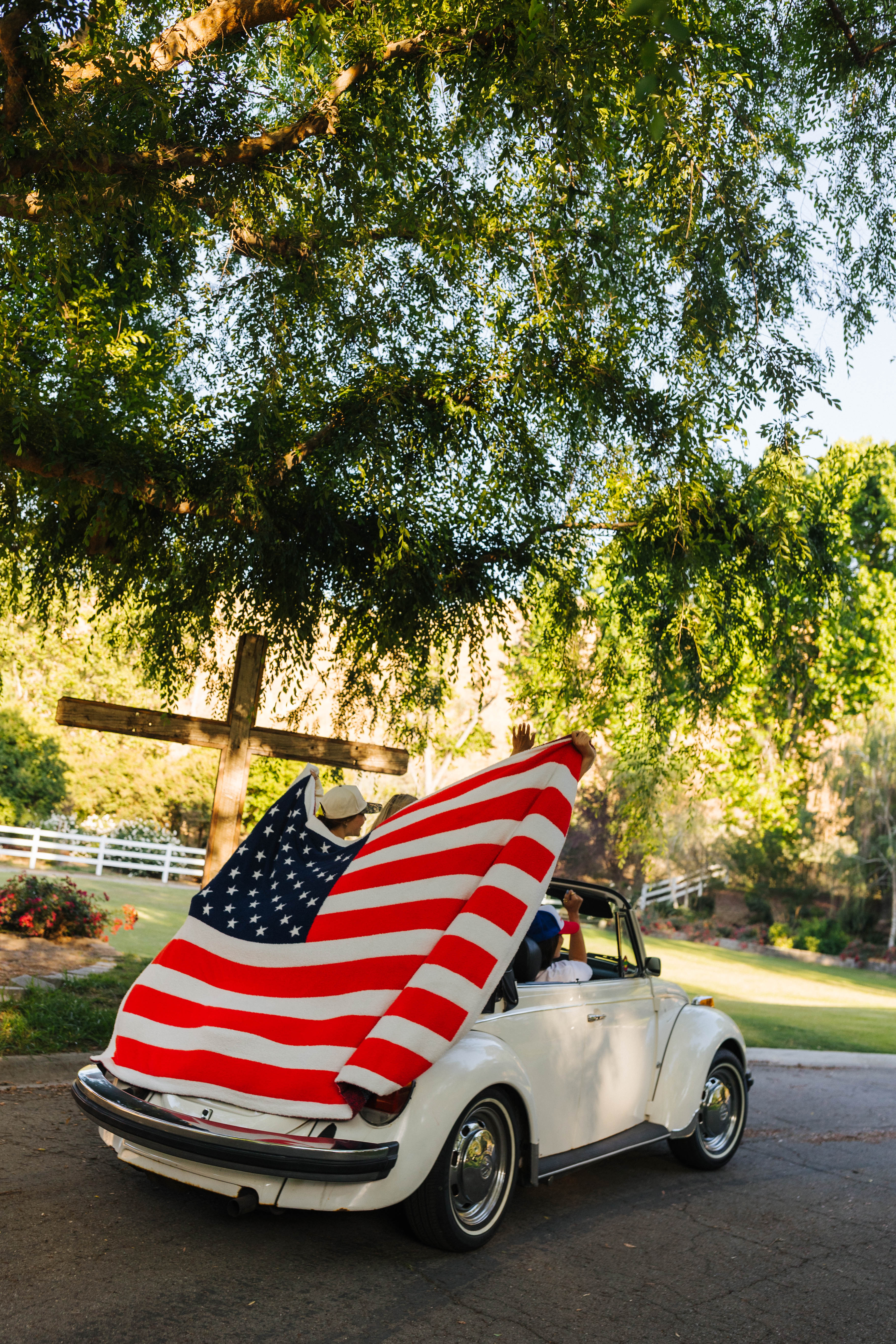 american flag blanket being held up while the car is driving