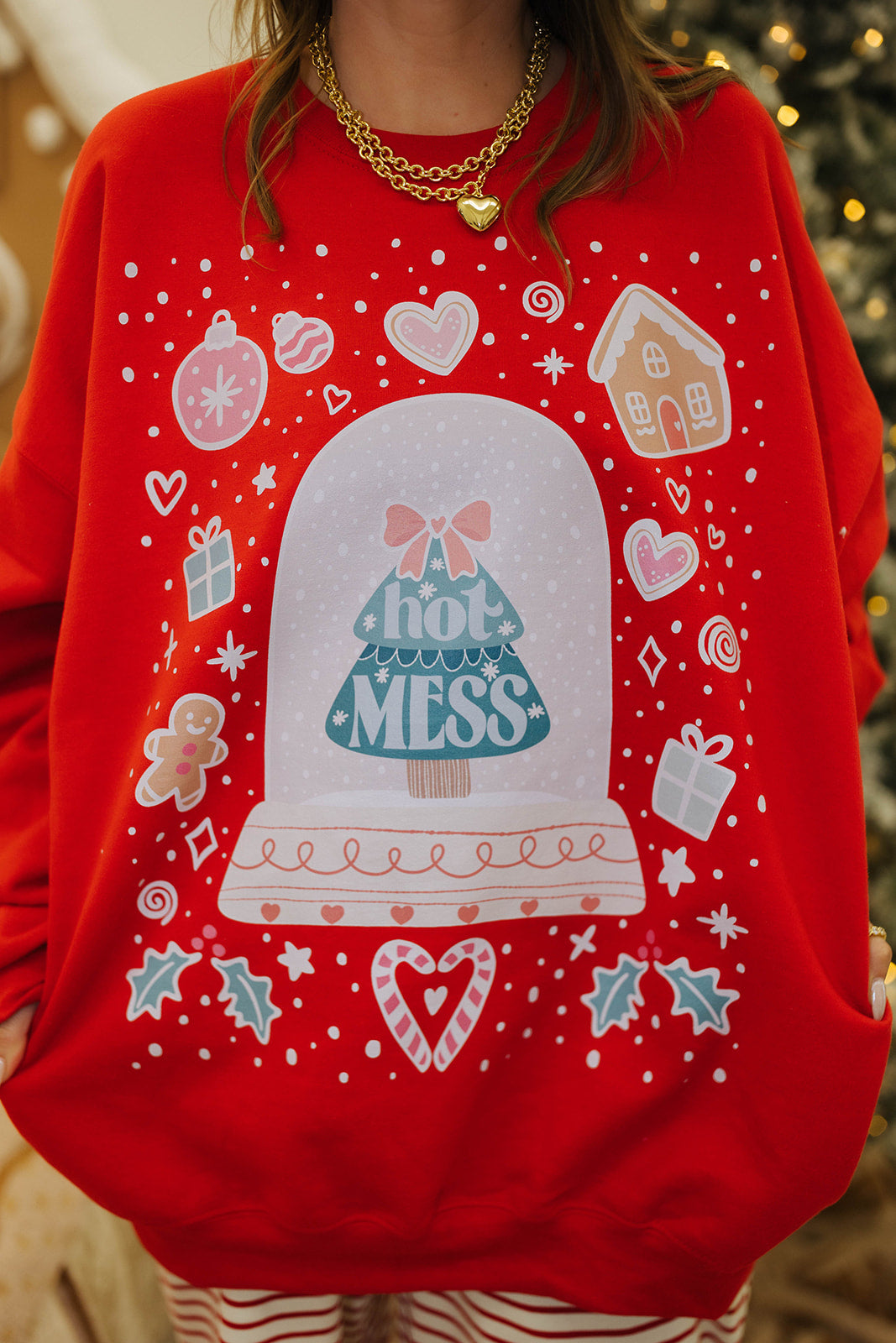 Red sweater with a snow globe design and 'Hot Mess' text, worn by a person.