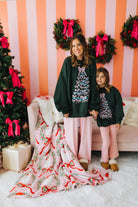 Two women in matching outfits standing in a festive room with Christmas decorations.