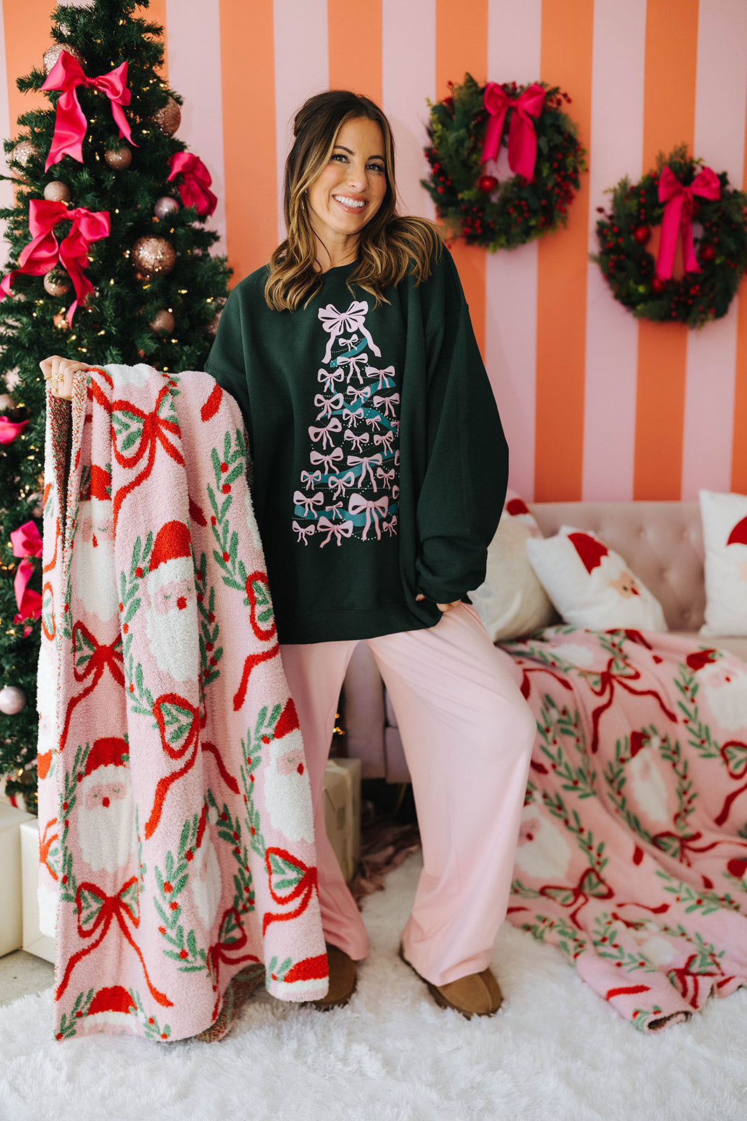 Woman in festive room with Christmas tree, wreaths, and pink and red bow-themed decor.