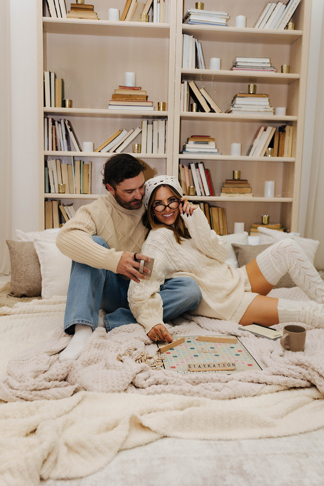 Couple sitting on a couch in a cozy living room with bookshelves in the background.