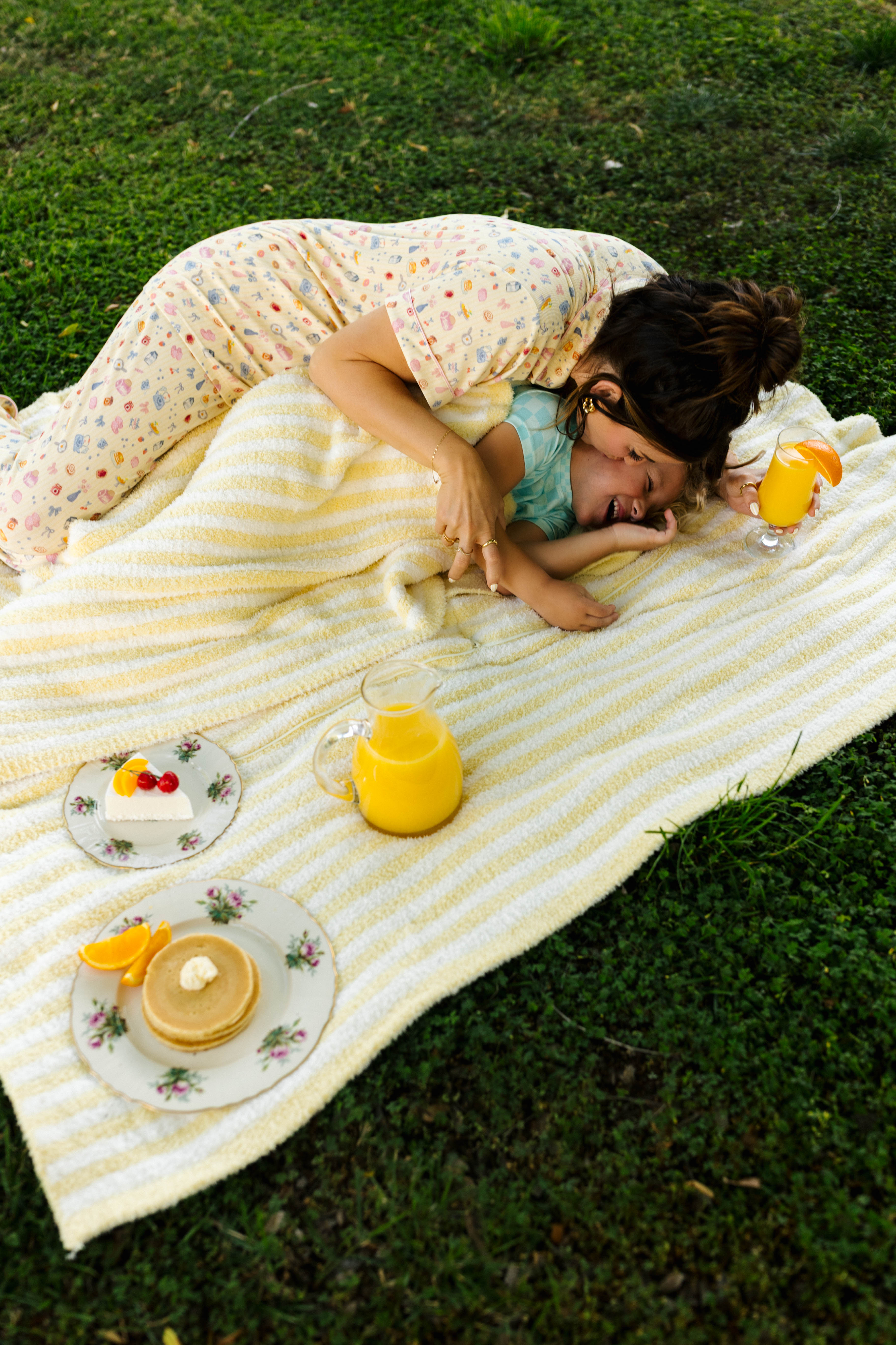woman lying on quillow with blanket on child