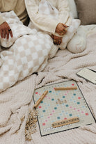Person wrapped in a blanket with a cozy-themed board game on a soft surface