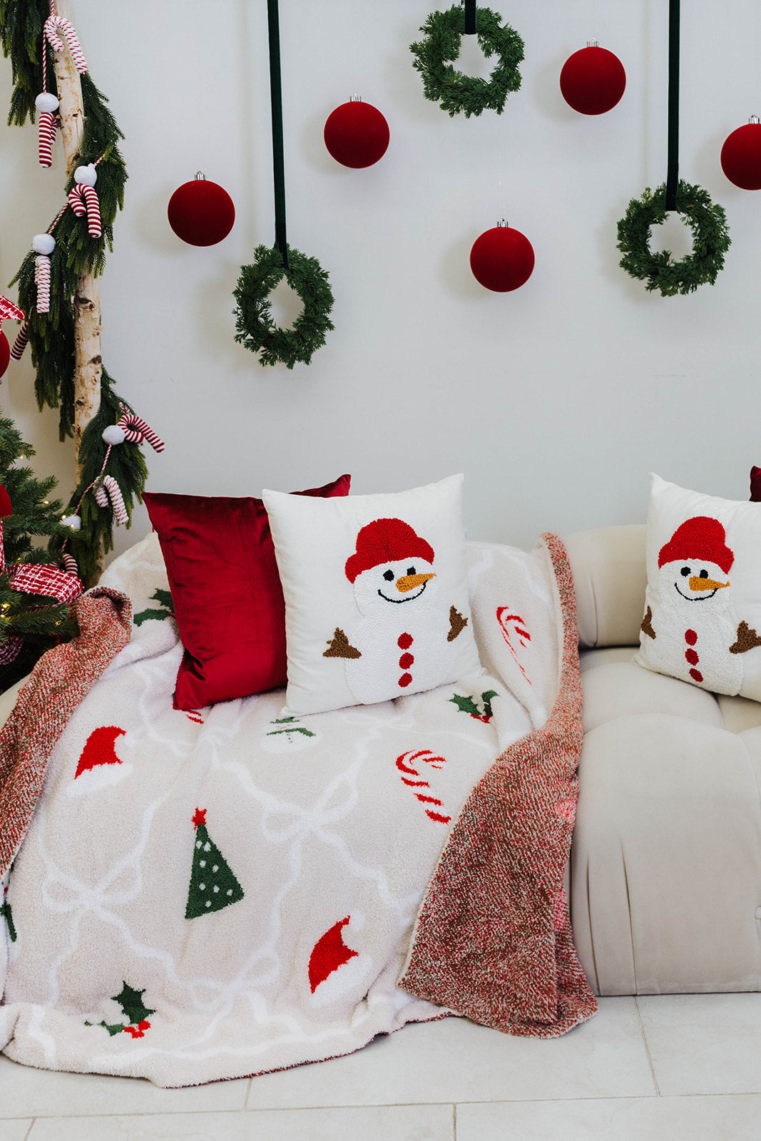 Decorative Christmas scene with a couch, pillows, and a blanket featuring festive designs.