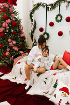 Woman and child sitting on a couch in a festive room with Christmas decorations.