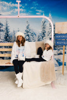 Two women sitting on a ski lift with a snowy landscape in the background