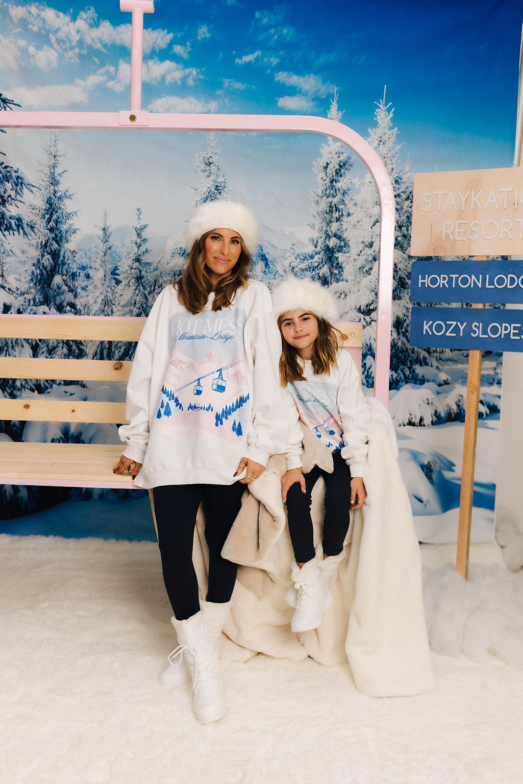 Two people posing on a ski lift with a snowy landscape background