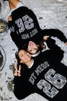 Mother and daughter laying in matching sweatshirts over a new years background 